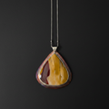 A teardrop-shaped pendant necklace featuring a polished yellow and reddish-brown agate stone set in a silver-toned bezel, suspended from a thin silver chain against a dark background.