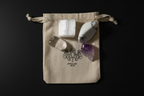 Four raw crystal stones arranged on a beige fabric drawstring pouch with a black printed logo that reads 'JEWELLERY BY J.R.
