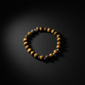 A beaded stretch bracelet featuring round brown and yellow tiger's eye beads accented with small metallic silver beads, displayed on a dark black background.