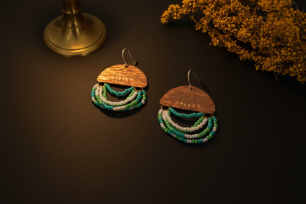 A pair of handmade dangle earrings displayed on a dark surface. Each earring features a semi-circular wooden top piece engraved with 'I LOVE YOU' in Spanish, hanging from silver fishhook wires.