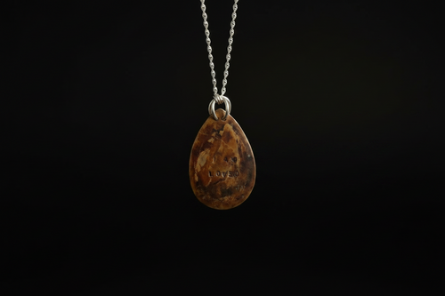 A teardrop-shaped brown gemstone pendant with natural inclusions, suspended from a silver chain against a solid black background.